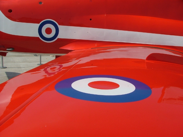 Ein rotes Flugzeug in der Mitte des Bildes mit einem Boden auf der linken Seite.