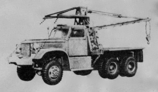 Ein Schwarz-Weiß-Foto eines großen, vierrädrigen Lkw mit einem Kran auf der Ladefläche und einem Anhänger.