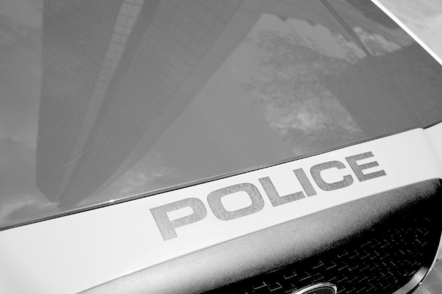 Ein Polizeiwagen mit einer Reflexion eines Gebäudes und Baums auf seiner Oberfläche.