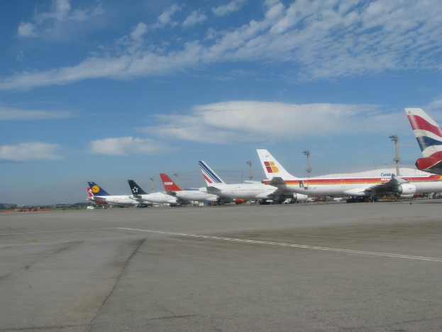 Eine Start- und Landebahn mit einigen Flugzeugen, Masten, Kabeln und einer bewölkten Himmel
