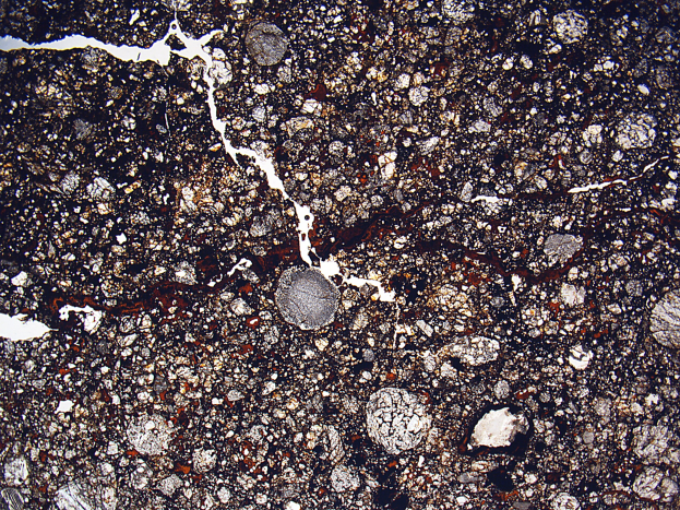 Nahaufnahme einer rissigen, schmutzbedeckten Straße mit rauer, unebener Oberfläche.