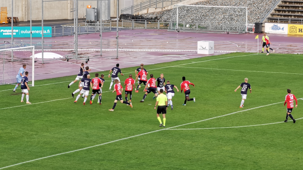 Eine Gruppe von Menschen, die Fußball auf einem Feld mit Zuschauern in einem Stadion spielen.