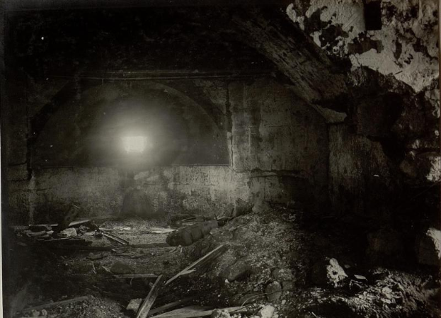 Altes Schwarz-Weiß-Foto eines zerfallenden Tunnels in den Ruinen der Berliner Mauer, mit Schutt auf dem Boden und einem Licht am Ende.