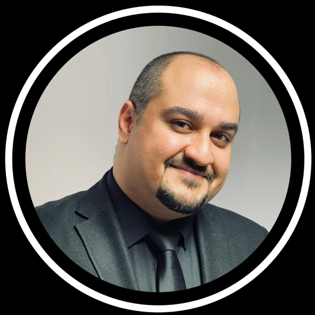 Ein Mann in Anzug und Krawatte mit einem freundlichen Gesichtsausdruck vor einem schwarzen Hintergrund, beschriftet als Anwalt in New York City.