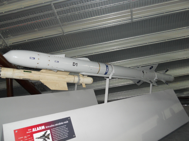 Raketen werden mit einer weißen Tafel am Boden gezeigt, auf der ein rotes und graues Plakat mit Text auf der linken Seite und ein weißes Dach oben zu sehen ist.
