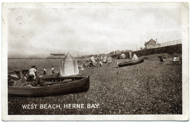 Schwarzes und wei├čes Foto von Menschen am Weststrand in Herne Bay mit Booten im Vordergrund, H├Ąusern und einem Zaun im Hintergrund und Text unten.