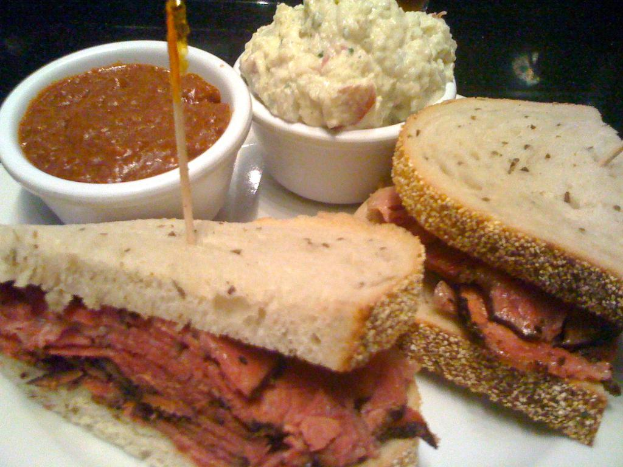 Ein Servierteller mit belegten Sandwiches und zwei Schalen Dip.