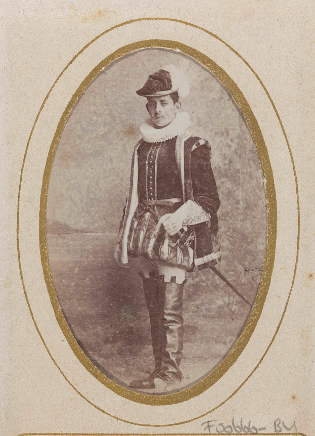 Ein altes Foto eines Mannes in traditioneller schottischer Kleidung, einschließlich Kilt, weißem Hemd, schwarzer Weste und schwarzem Hut, der entschlossen mit einem Schwert in der Hand steht.