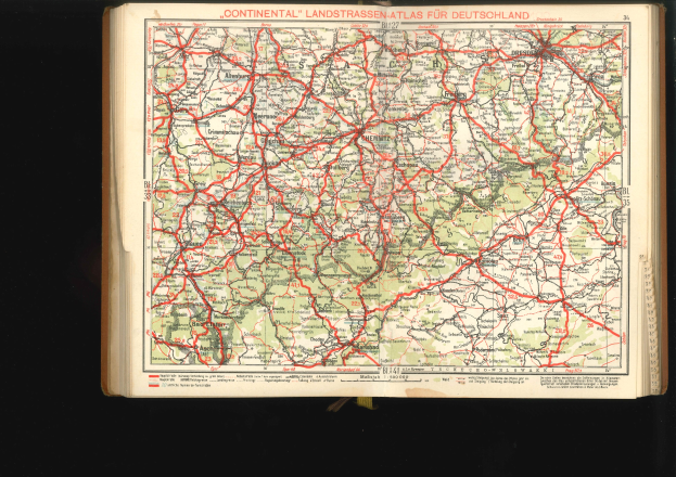 Offenes Buch mit einer detaillierten Karte von Deutschlands Straßen und Autobahnen vor schwarzem Hintergrund.