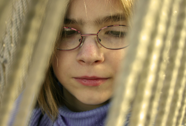 Ein M├Ądchen mit Brille vor einem Seil-Hintergrund.