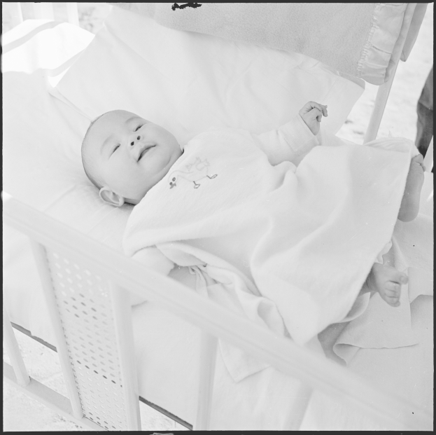 Ein Schwarz-Weiß-Foto eines friedlich schlafenden Babys in einer Wiege, in eine Decke gewickelt.