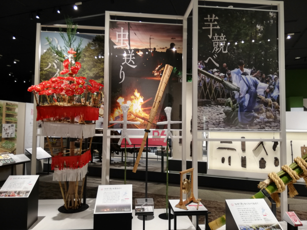 Ein Raum voller verschiedener Gegenstände, darunter Schilder mit Text, Stände und andere Objekte, mit Schildern mit Bildern und Text sowie Lichtern an der Decke, die eine festliche Atmosphäre für die Tokyo Toy Fair 2019 schaffen.
