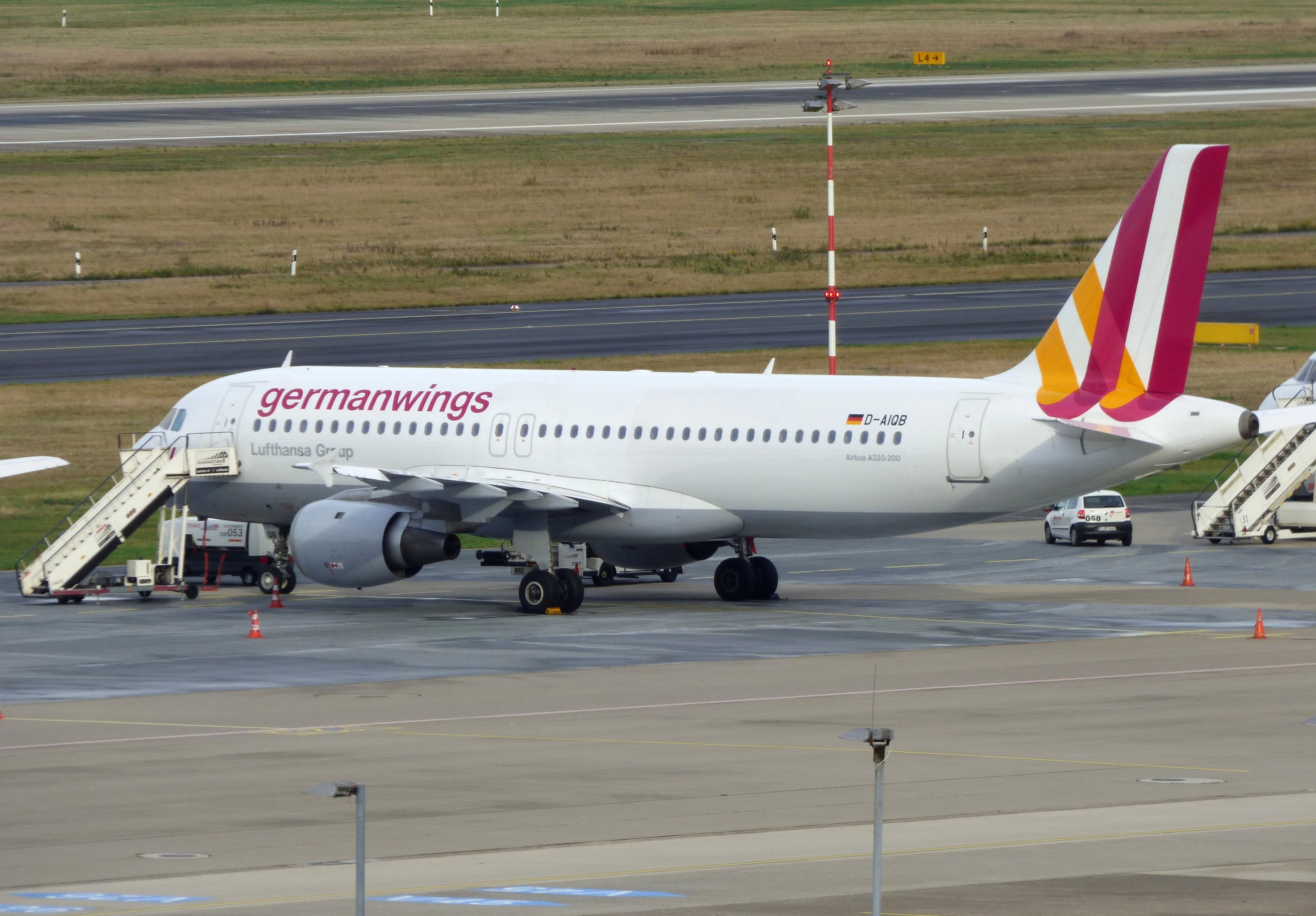 Germanwings Airbus A320-200 geparkt am Frankfurter Flughafen mit Bodenfahrzeugen, Verkehrskegeln, Pfählen und Gras im Hintergrund.