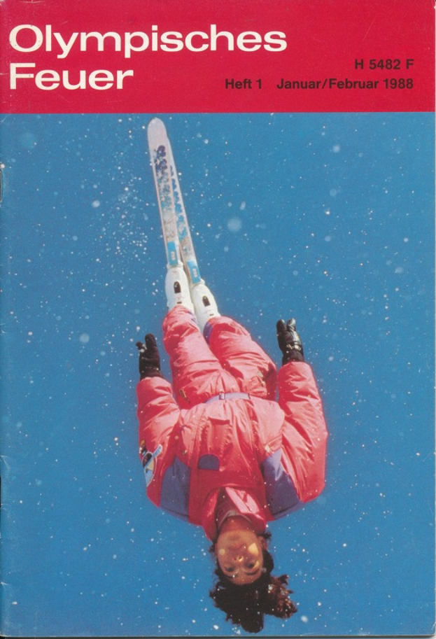 Ein Buchumschlag mit einem Skispringer in der Luft, der einen Skianzug trägt und auf dem Titel 'Olympische Spiele Feuer - Heft 1 - Januar/Februar 1988' deutlich zu sehen ist.