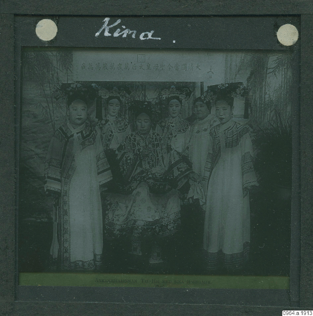 Ein Schwarz-Weiße-Foto einer Gruppe von Menschen in traditioneller chinesischer Kleidung, einige sitzen und einige stehen, mit Text oben.