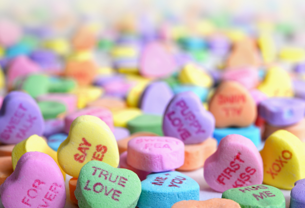 Ein Haufen bunter Herzchen mit der Aufschrift 'True Love' vor einem unscharfen Hintergrund.