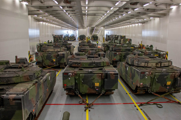 Eine gro├če Militarauebung mit Reihen von Militaraefahrzeugen, Wanden auf beiden Seiten und Deckenbeleuchtung.