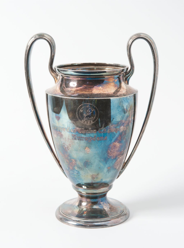 Der UEFA-Champions-League-Pokal, ein stählerner Becher mit zwei Griffen und einem blauen und silbernen Farbschema, der mit "UEFA Champions League" beschriftet ist.