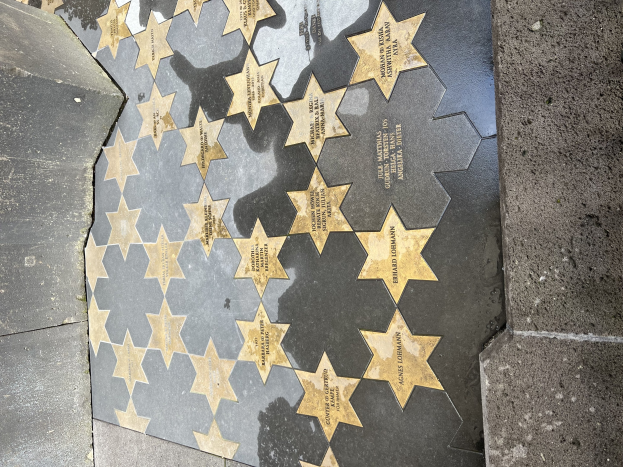 Fünf miteinander verbundene Sterne mit eingraviertem Text auf dem Hollywood Walk of Fame, flankiert von Wänden in Los Angeles, Kalifornien.