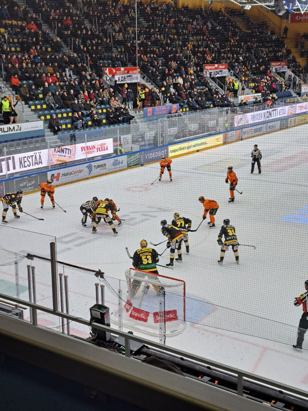 Gruppe von Menschen, die Hockey auf einem Eisstadion mit Zuschauern, Bannern und Scheinwerfern spielen