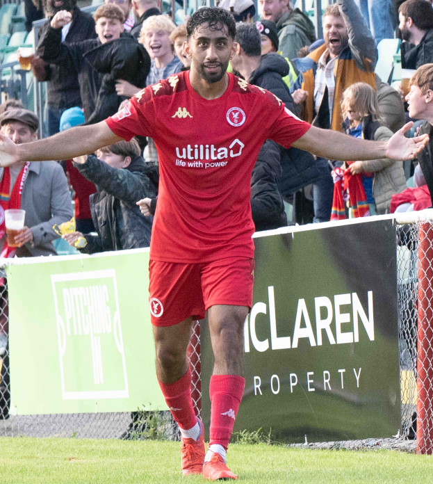 Ein Fußballspieler in roter Uniform rennt mit ausgebreiteten Armen auf einem Feld, im Hintergrund ist eine Menge zu sehen und ein Banner mit der Aufschrift "Middlesbrough FC v Swansea City - Sky Bet Championship" im Vordergrund.