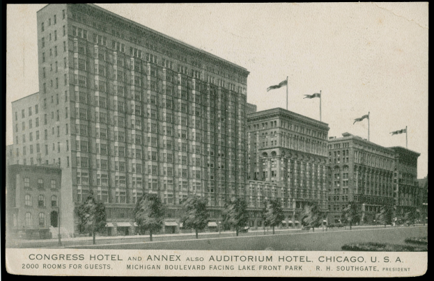 Ein Schwarz-Weiß-Foto des Congress-Hotels und des Annex-Auditorium-Hotels in Chicago, Illinois, ein großes Gebäude mit vielen Fenstern, umgeben von Bäumen und Fahnenstangen, mit einem klaren Himmel im Hintergrund und Text am unteren Rand des Bildes.