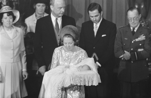 Königin Elizabeth II hält das Neugeborene Prinz Philip in ihren Armen, während Prinz Philip, Duke of Edinburgh, neben ihr in einem Anzug und Krawatte steht, mit Vorhängen im Hintergrund.