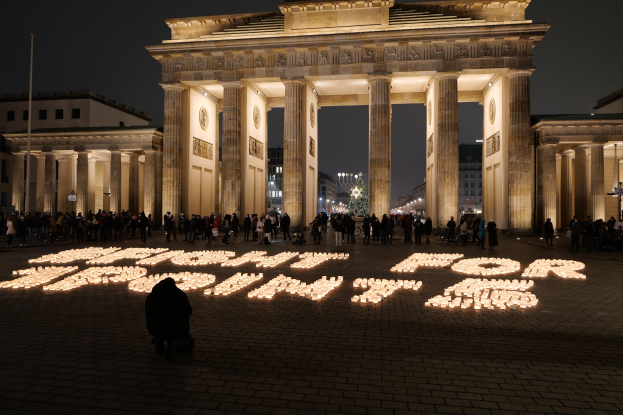 Gruppe von Menschen, die vor dem beleuchteten Brandenburger Tor in Berlin, Deutschland, mit der Aufschrift 'Kampf für die Freiheit' im Vordergrund stehen.